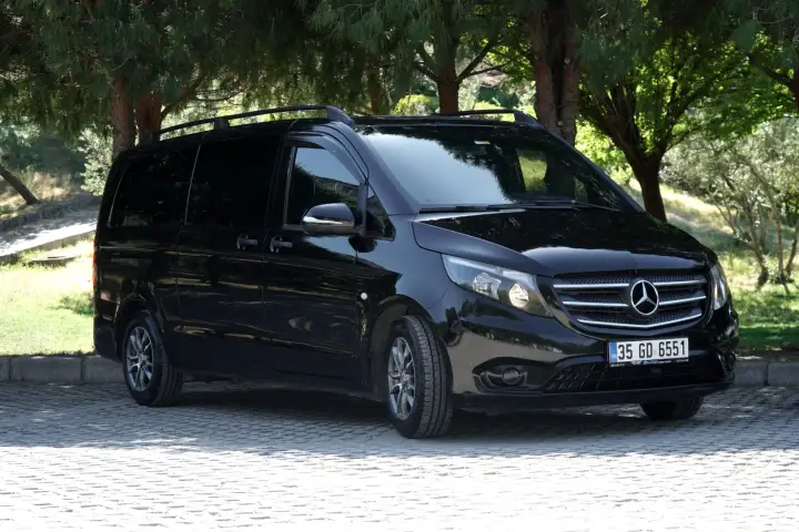 Ağaçların yanında siyah Mercedes özel transfer aracı, yandan görünüm