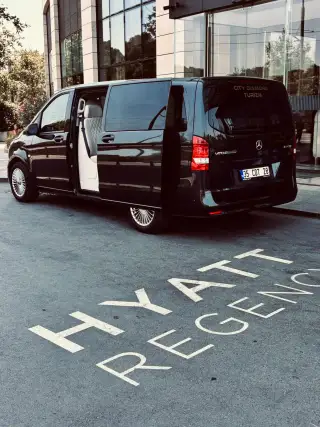 Schwarzes Mercedes-Transferfahrzeug mit offener Tür am Hoteleingang