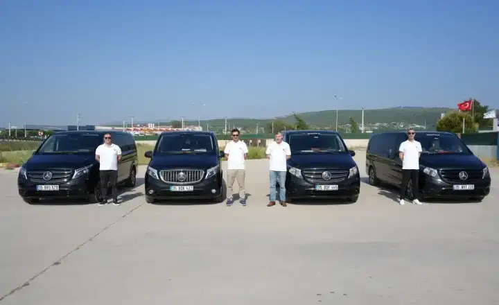 Transferiste Fahrerteam neben einer Reihe von Mercedes Transferfahrzeugen