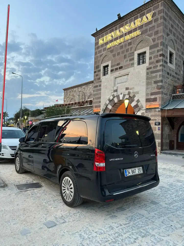 Taş kule önünde park edilmiş siyah Mercedes Vito