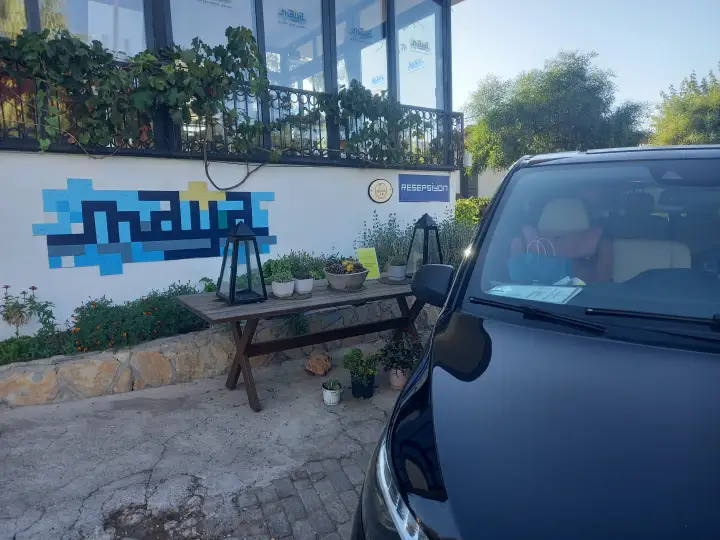 Bahçe duvarı ve açık hava oturma alanı yanında siyah Mercedes Vito