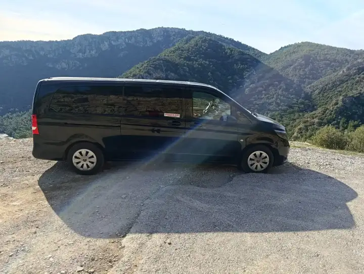 Dağlık manzara önünde park edilmiş siyah Mercedes Vito