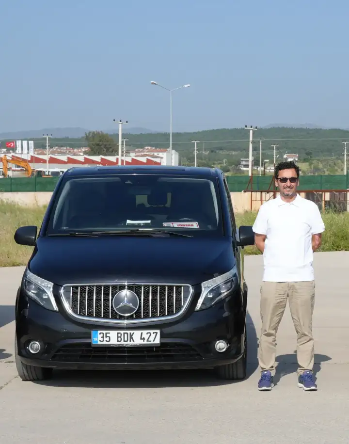 Siyah Mercedes transfer aracının yanında duran sürücü