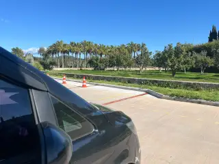 Ağaçlarla çevrili giriş yolunda siyah transfer aracının ön kısmı