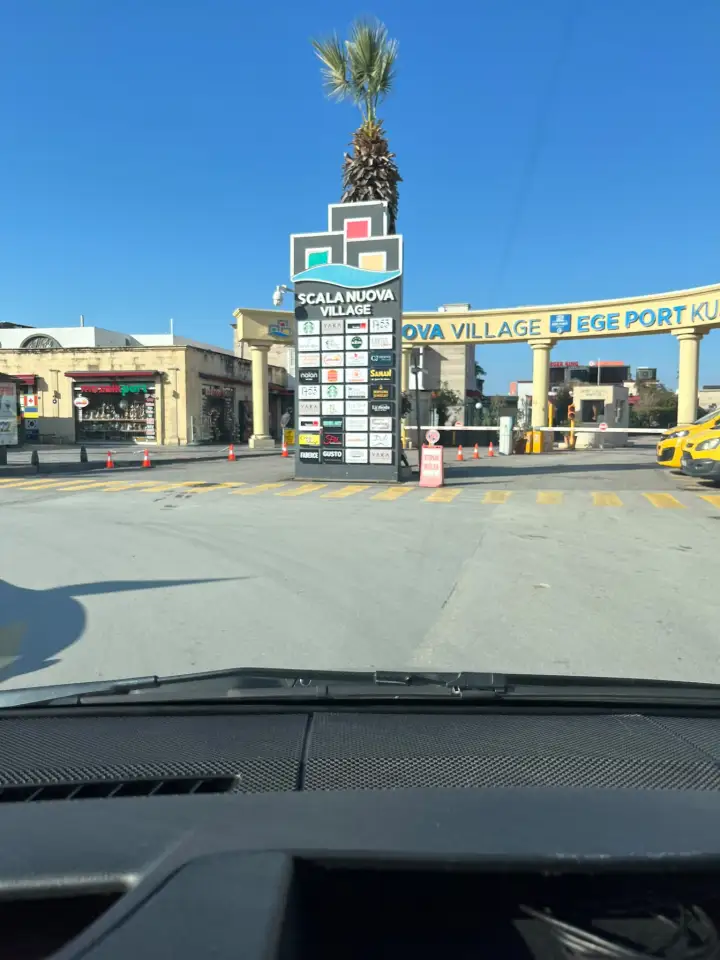 Kuşadası liman girişinde Scala Nuova Village ve Ege Port tabelaları, araç bariyerleri ve yaya geçidi